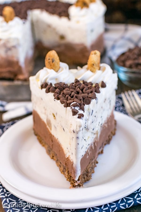 A white plate with a slice of chocolate chip cookie dough ice cream cake on it
