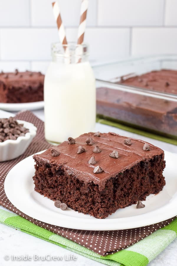 A white plate with a slice of zucchini brownies topped with chocolate frosting.