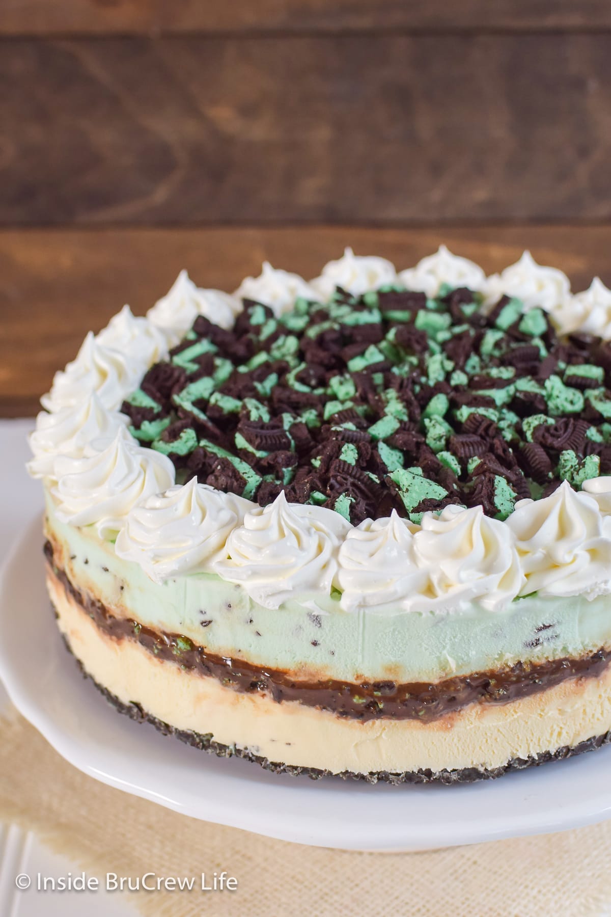 A white cake plate with a layered ice cream cake on it.