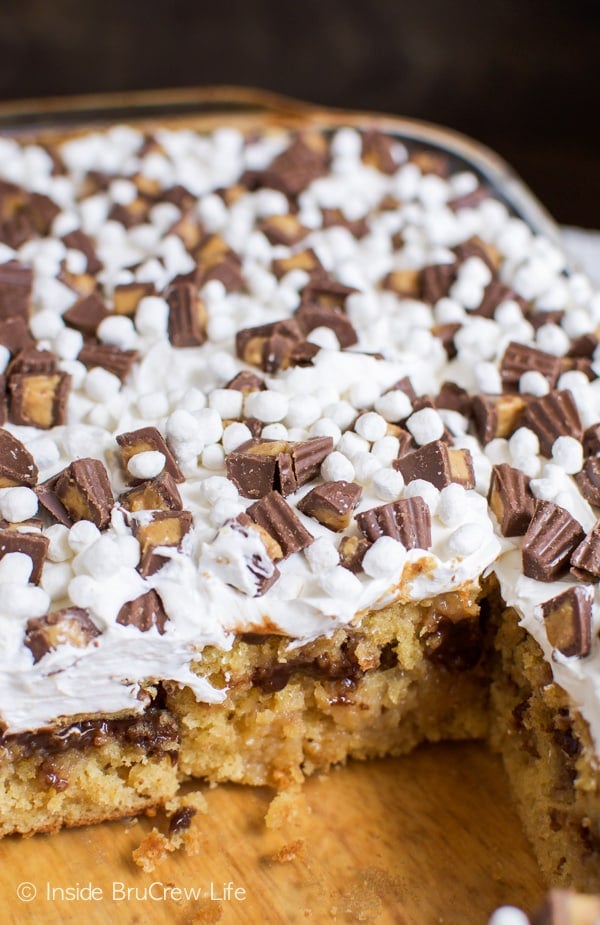 A picture of the inside of a pan of peanut butter fudge poke cake topped with peanut butter cups and marshmallow bits