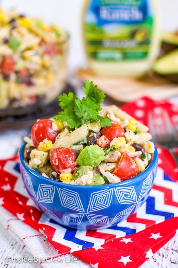 A blue bowl filled with a southwest pasta salad with a bigger bowl of salad behind it