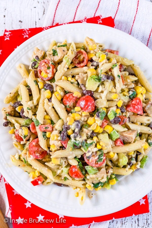 A large white bowl on a red towel filled with a southwest ranch pasta salad