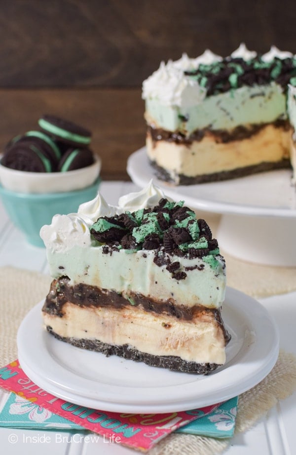 A slice of vanilla mint chip ice cream cake on a white plate with more cake behind it