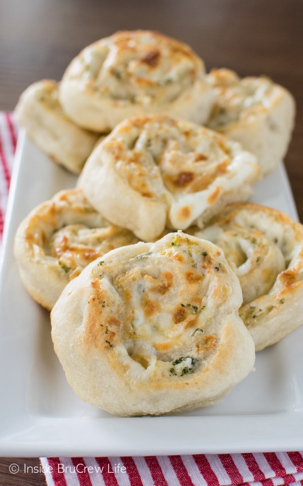 Pinwheel appetizers stuffed with cheese, broccoli, and chicken on a white plate.