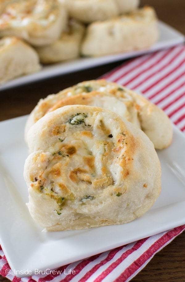 2 chicken and broccoli pizza wheels on a white plate.