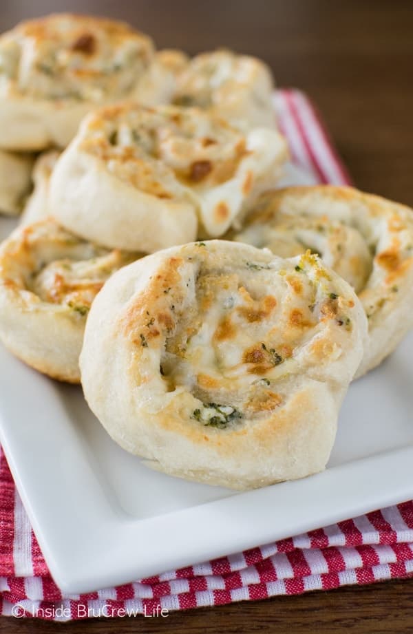 Pizza wheel appetizers stacked on a white plate.