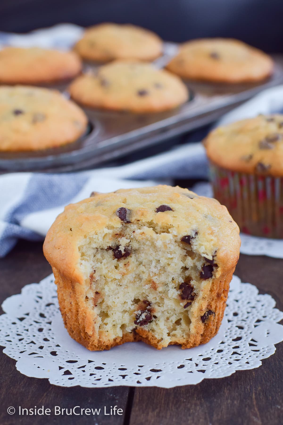 A fluffy banana muffin with a bite out of the front on white paper.