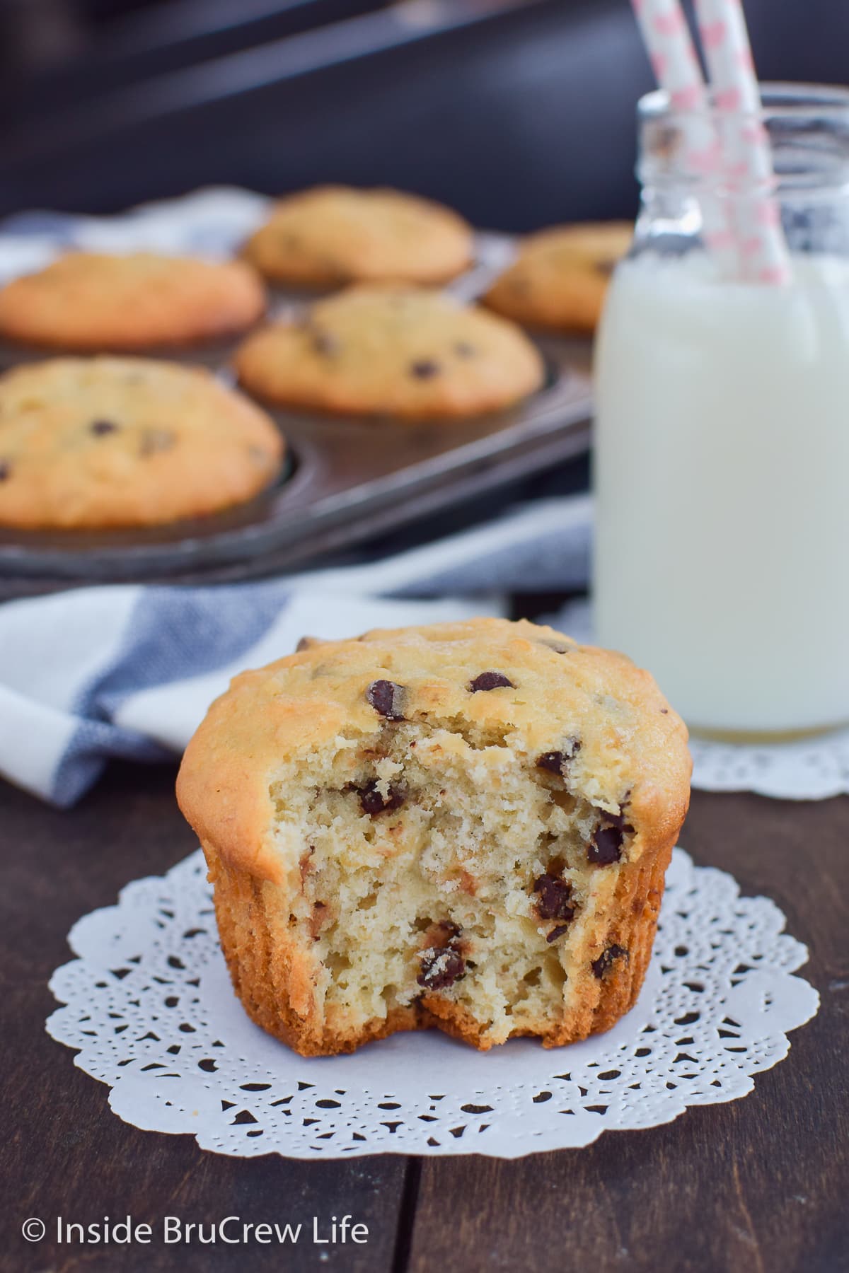 A fluffy banana muffin with a bite out of the front on white paper.