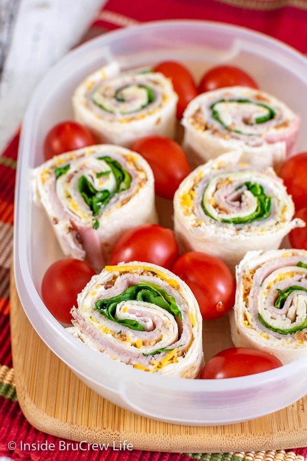 Turkey Club Pinwheels num recipiente de plástico transparente com tomates cereja