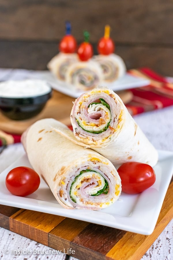 A turkey club pinwheel cut in half and stacked on a white plate