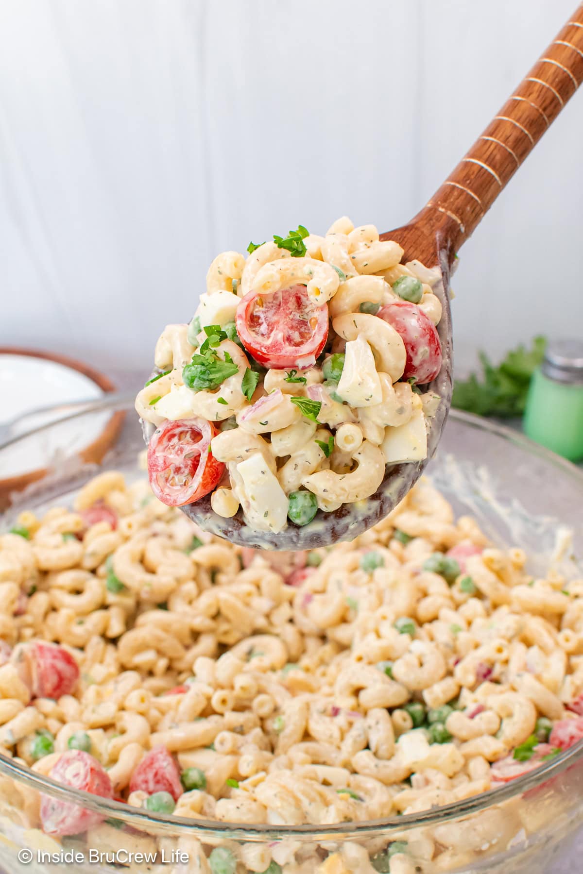 A scoop of pasta salad being lifted out of a bowl.