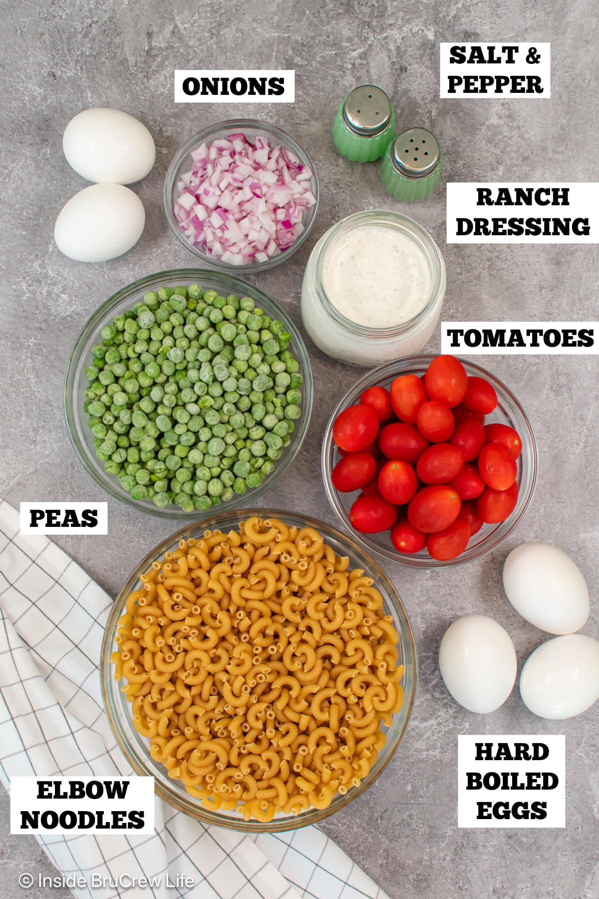 Bowls of ingredients needed to make pasta salad.