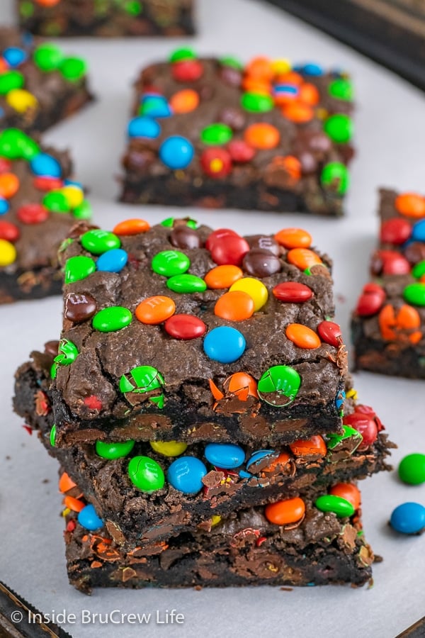 Three fudgy M&M brownies stacked on top of each other on a tray.