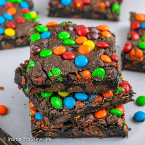 Three fudge brownies with M&M's stacked on a tray.