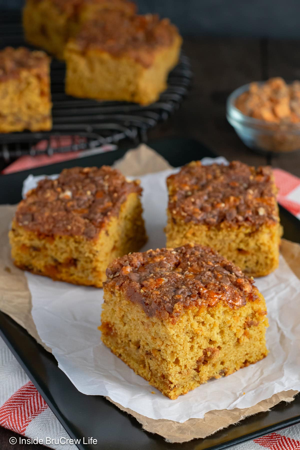 Squares of pumpkin cake on a black tray.