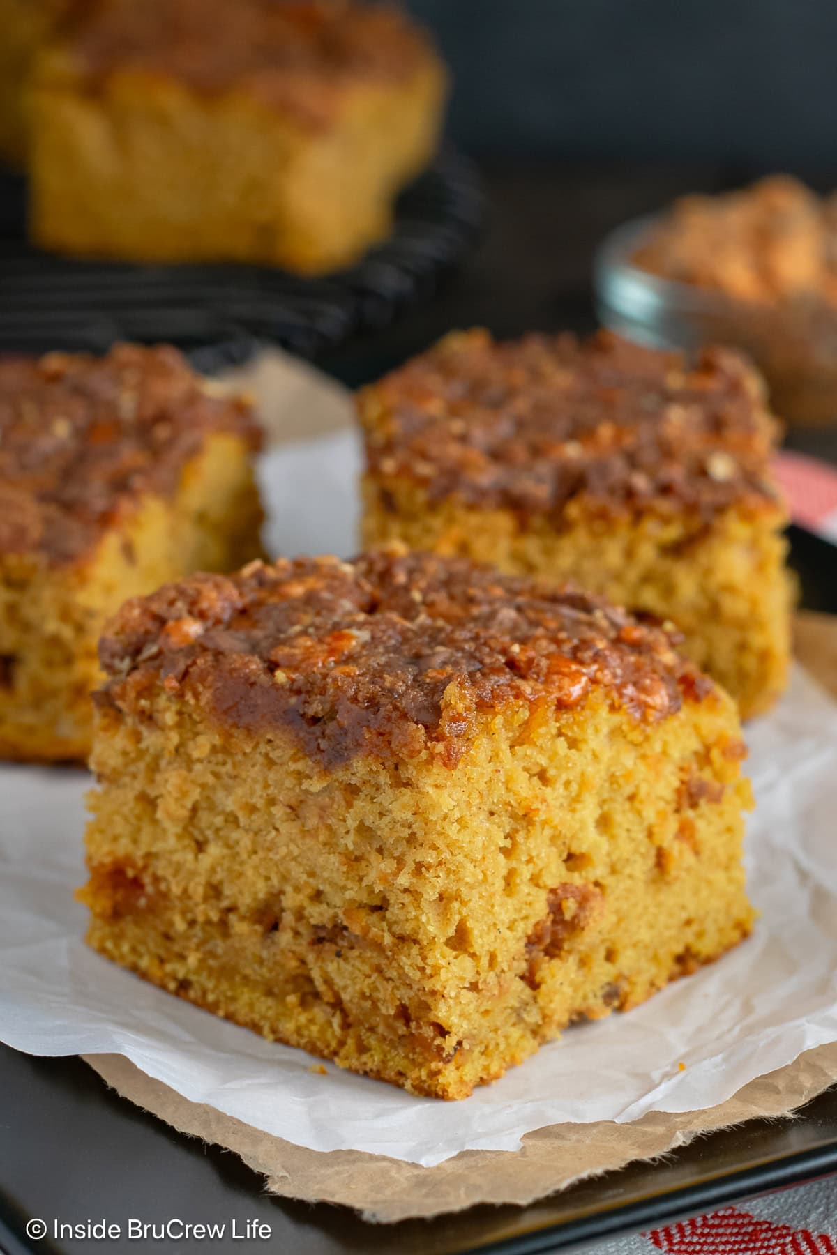 A square of pumpkin cake with a peanut butter crumble topping on a plate.