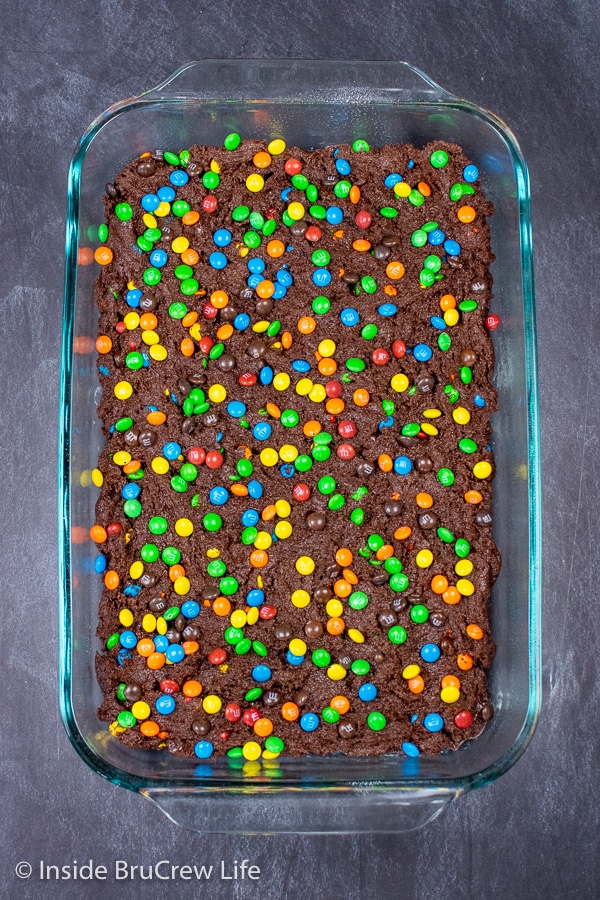 A glass pan with unbaked M&M's brownies in it.
