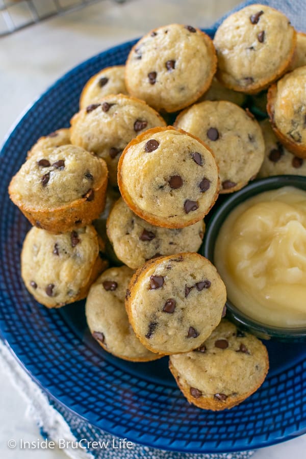 Overhead picture of mini pancake muffins on a blue plate with a bowl of honey butter