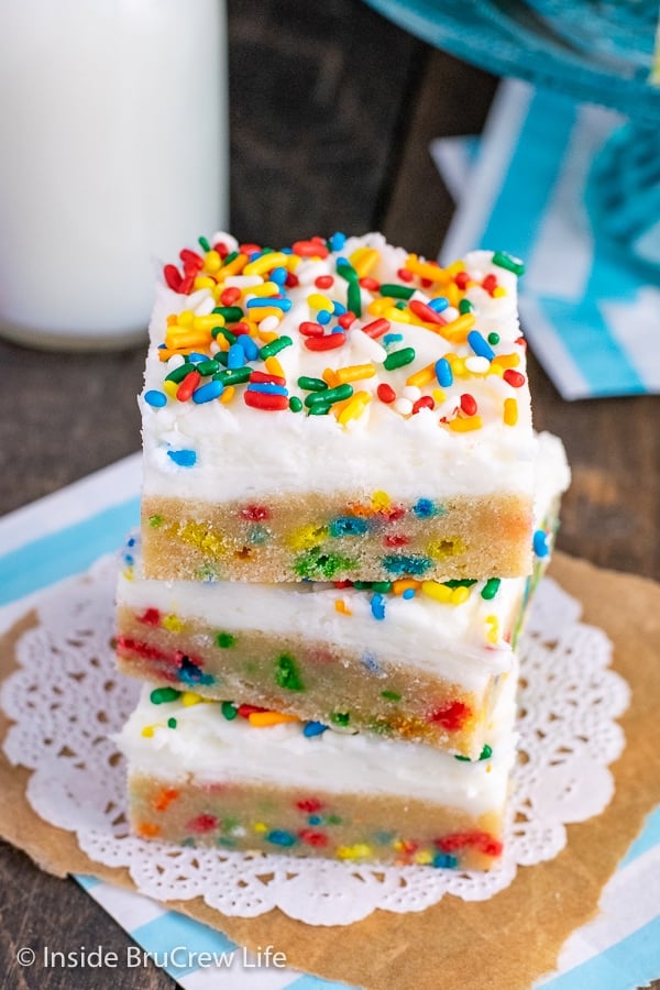 Three Funfetti sugar cookie bars with vanilla buttercream frosting stacked on top of each other