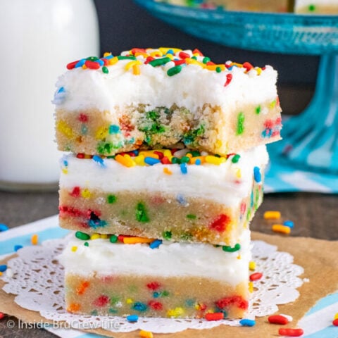 Three funfetti sugar cookie bars with vanilla buttercream stacked on top of each other