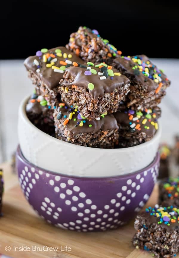 A white bowl filled with no bake chocolate granola bar bites that are topped with chocolate and sprinkles