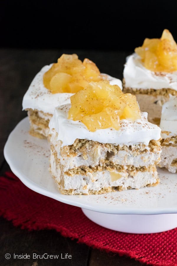 A white cake plate with squares of cinnamon apple icebox cake topped with scoops of homemade apple filling on top