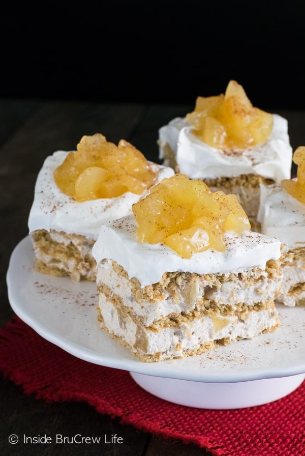 A white cake plate on a red towel with squares of apple icebox cake with apple pie filling on it