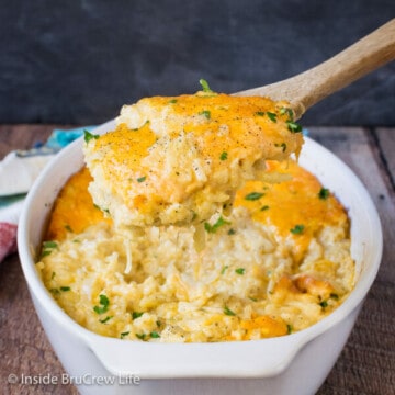 A white dish filled with cheesy hashbrown casserole and a spoon lifting some out.
