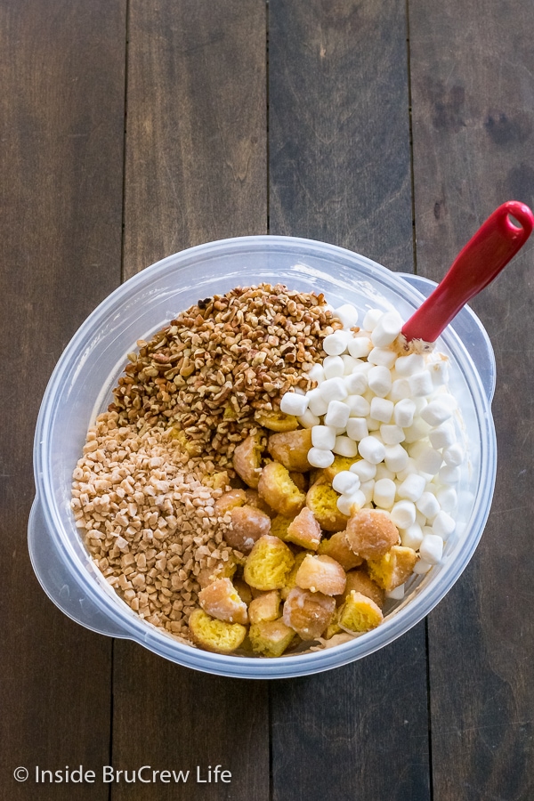 A bowl of pumpkin fluff salad with donut holes, toffee bits, nuts, and marshmallows on top