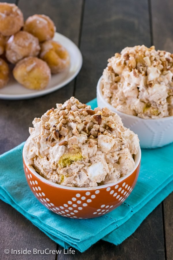 Two bowls on a teal towel filled with pumpkin fluff salad and topped with nuts and toffee