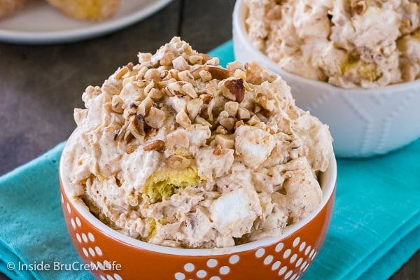 Pumpkin Fluff Salad topped with nuts and toffee in an orange bowl