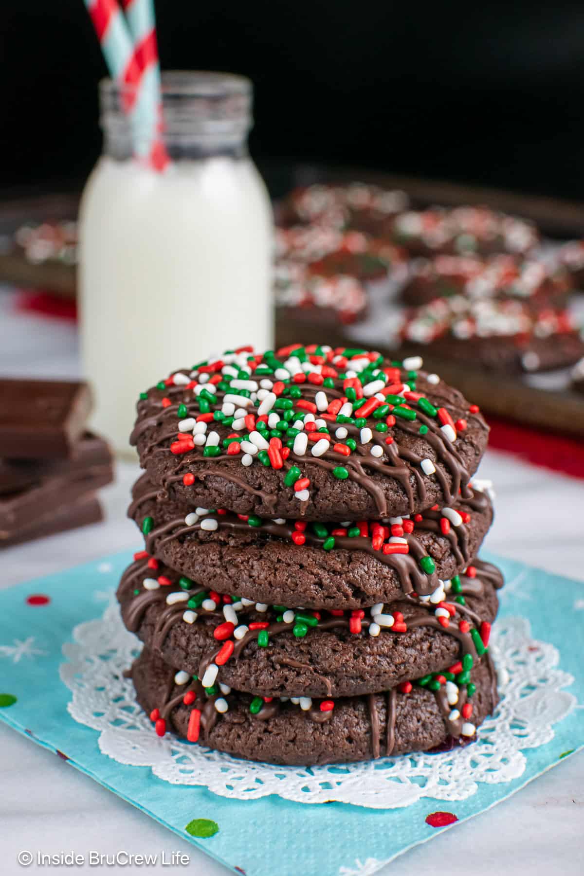 A stack of chocolate Christmas cookies and a cup of milk.