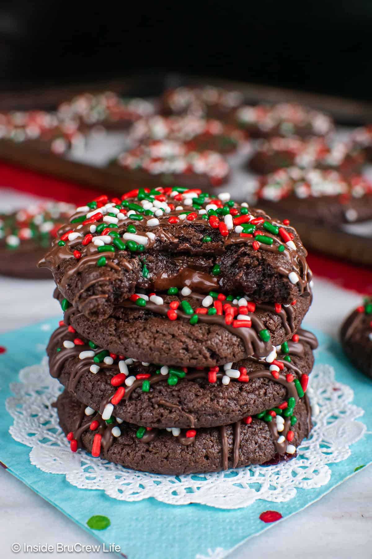 Chocolate Christmas cookies stacked in a pile with a bite out of the top showing the gooey center.