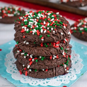 Four chocolate cake mix cookies decorated with Christmas sprinkles stacked in a pile.