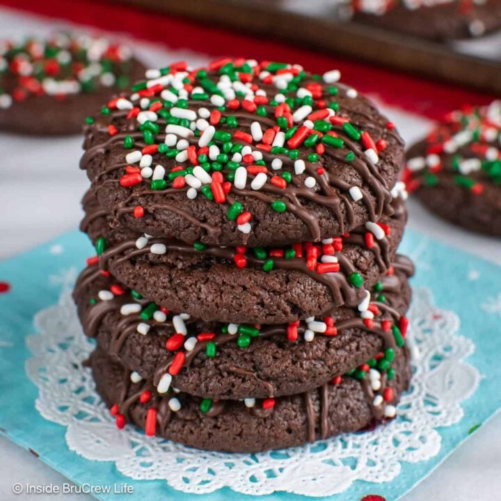Four chocolate cake mix cookies decorated with Christmas sprinkles stacked in a pile.
