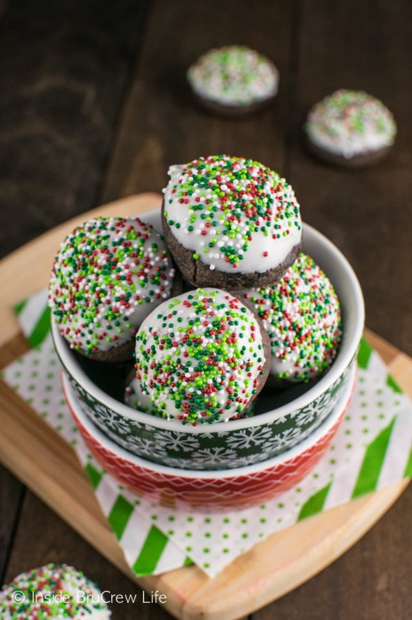 An overhead picture of a bowl filled with chocolate mint snowball cookies that are dipped in chocolate and have sprinkles