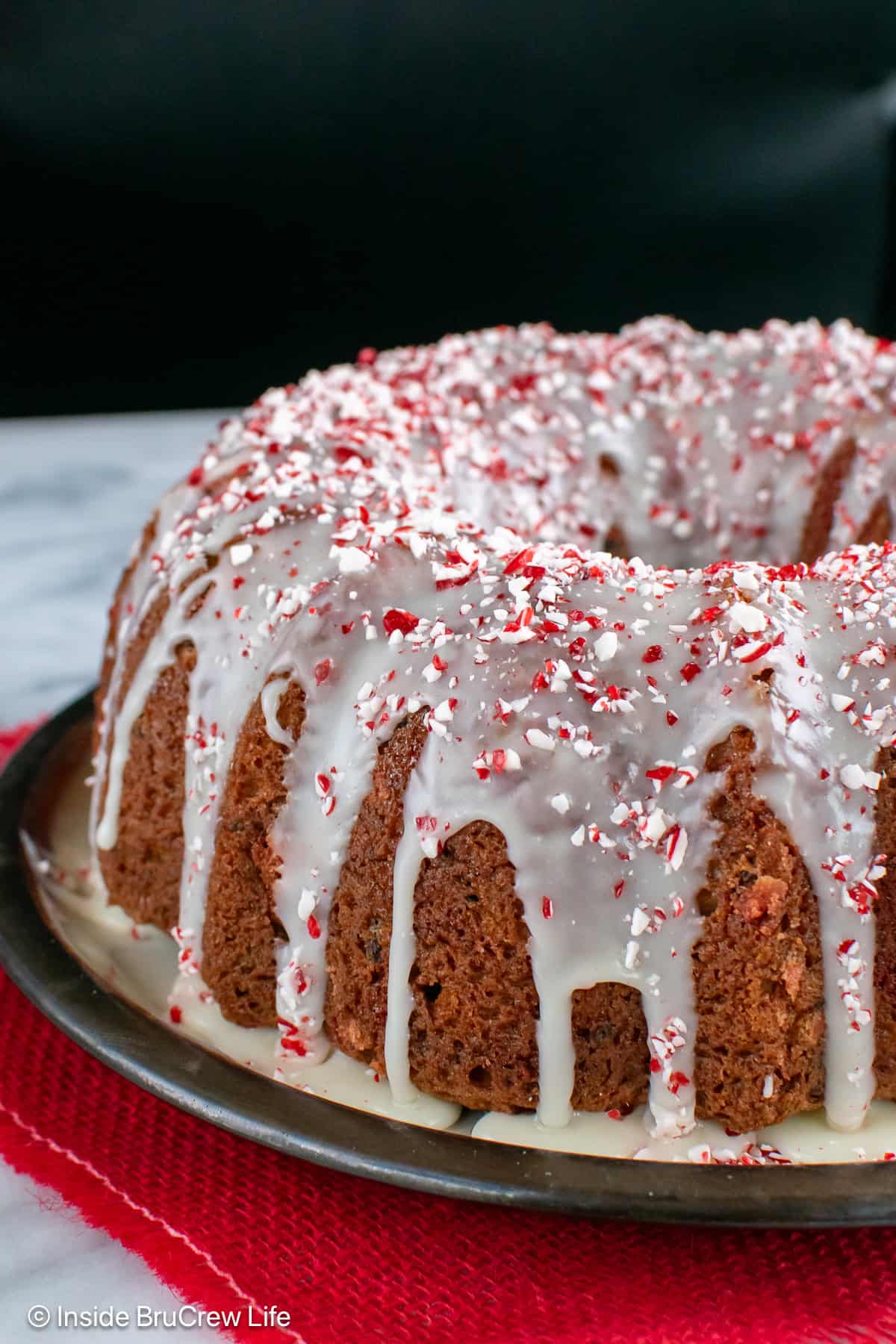 A peppermint bundt cake with white chocolate glaze on a plate.