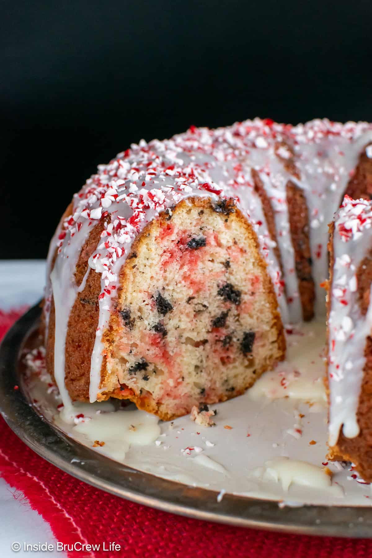 A glazed peppermint bundt cake with Oreo pieces on a plate.