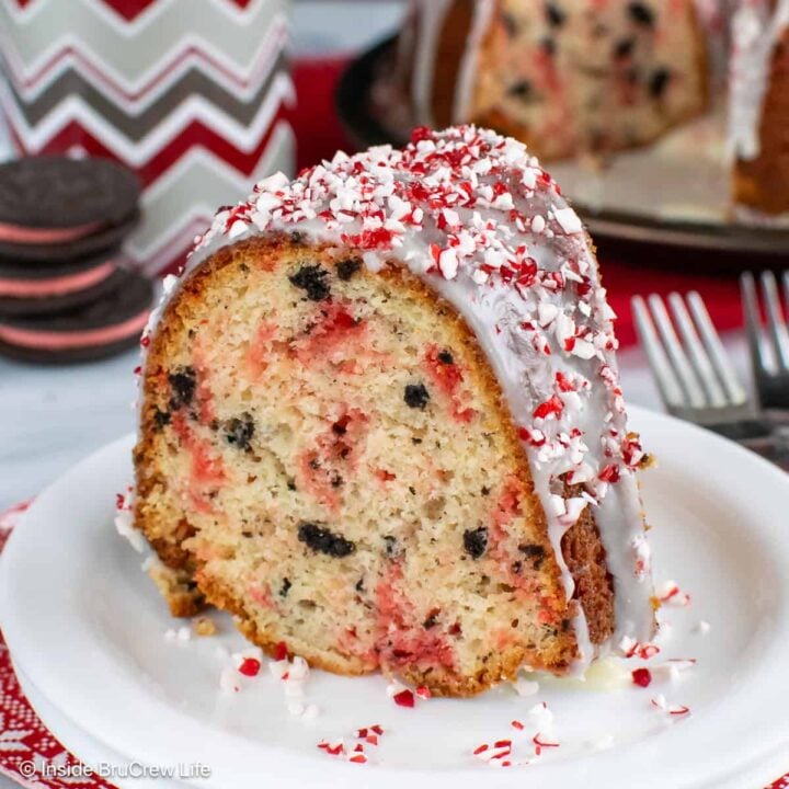 A slice of peppermint Oreo cake with a white chocolate glaze on a cake plate.