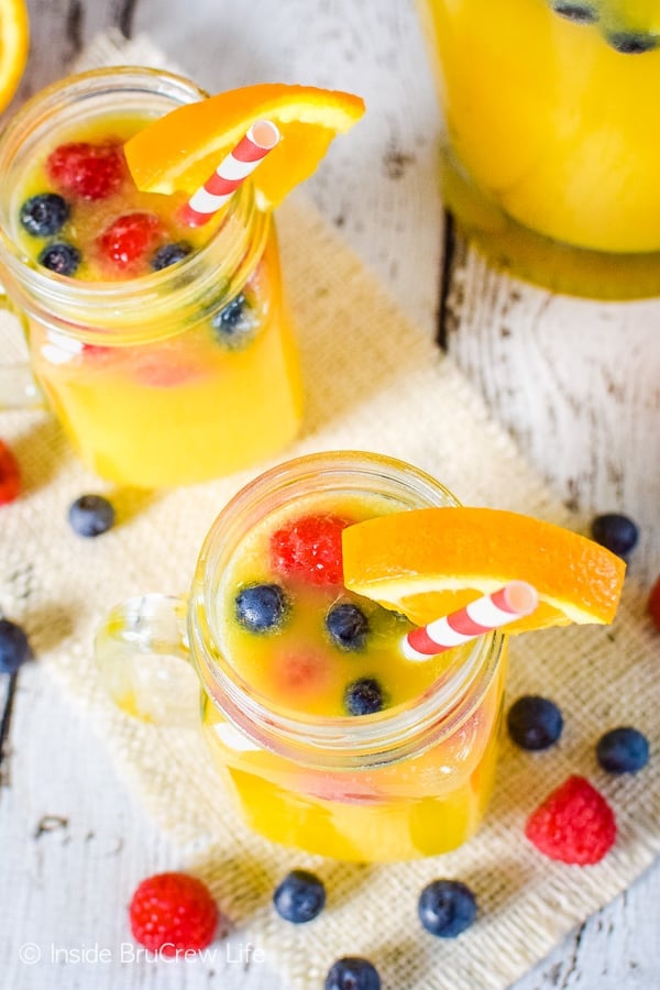 Overhead picture of two clear mugs filled with pineapple punch and fresh berries