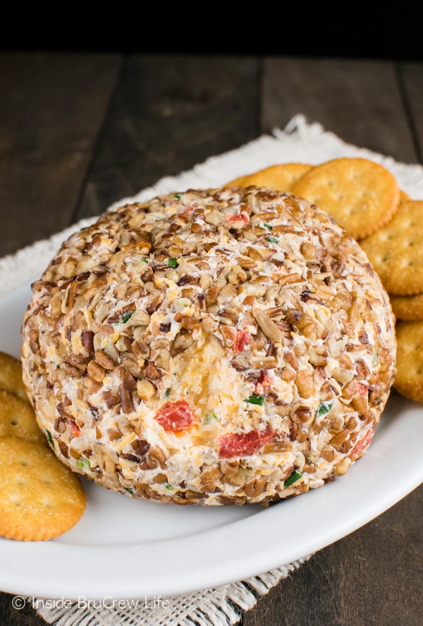 A cheese ball on a white plate with crackers.