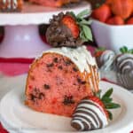 A slice of strawberry bundt cake topped with chocolate drizzles and a chocolate covered strawberry