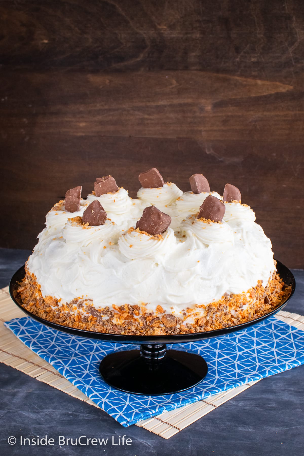 A frosted cake on a black cake plate.