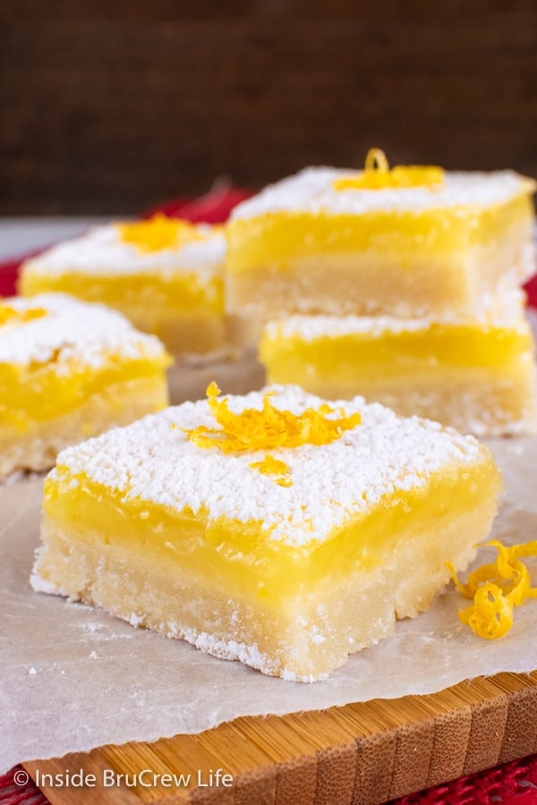 Cookie squares with powdered sugar on top on a wooden cutting board.