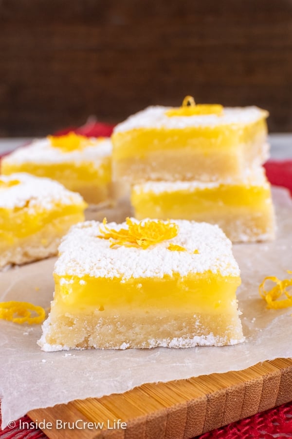 Lemon squares with powdered sugar on a wooden cutting board.