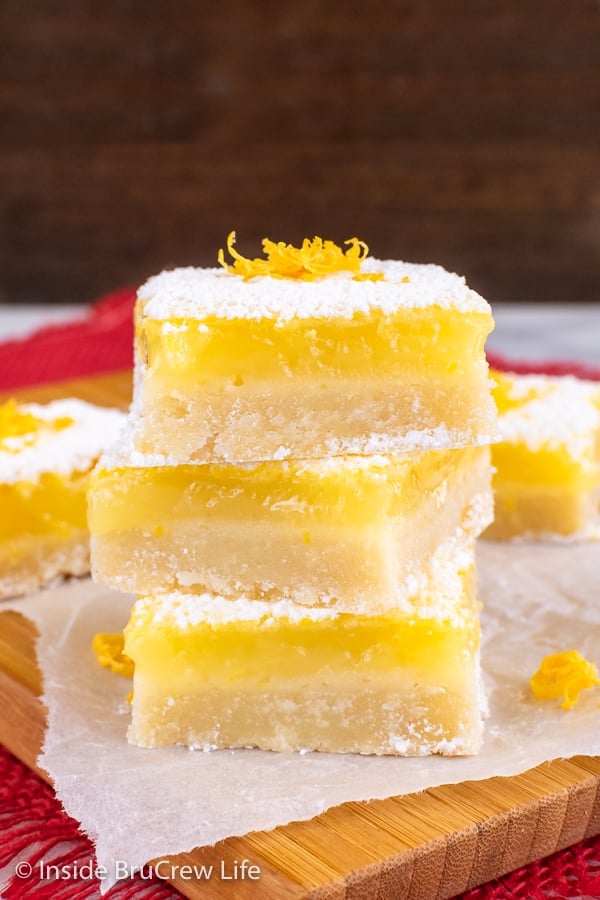 Three lemon cookie squares with powdered sugar stacked on top of each other.