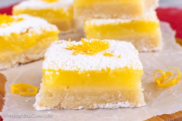 A close up of a cookie square topped with powdered sugar and lemon zest.