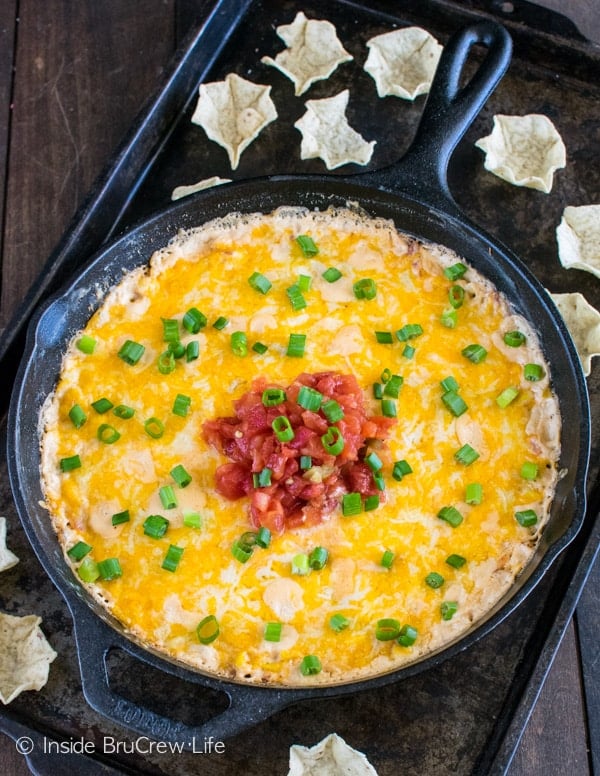 A cast iron skillet with corn dip covered in melted cheese.
