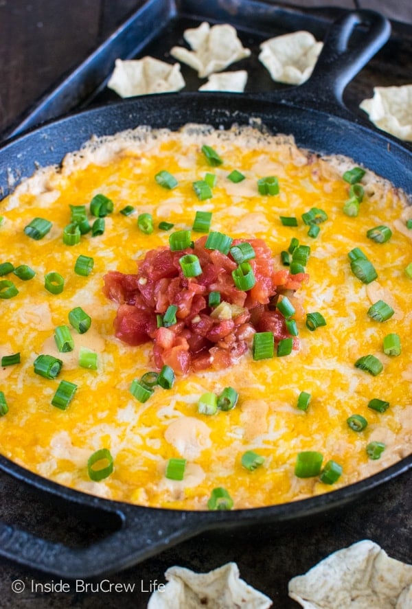 A cast iron skillet with a cheesy dip topped with salsa.