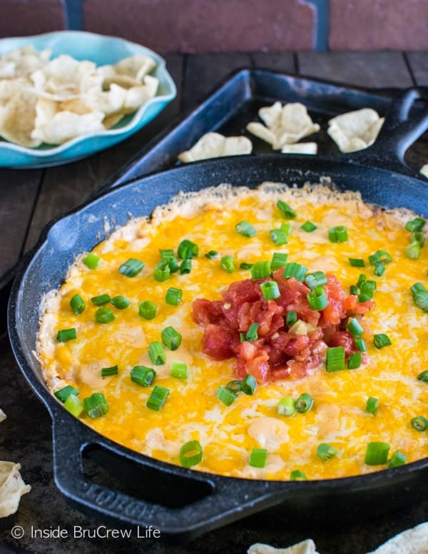 A cast iron skillet filled with hot corn dip covered in melted cheese.